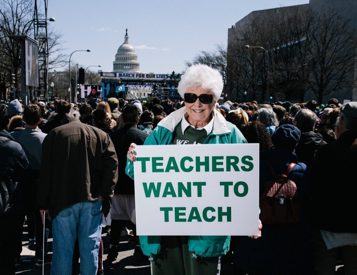 A woman stands with a sign that says 